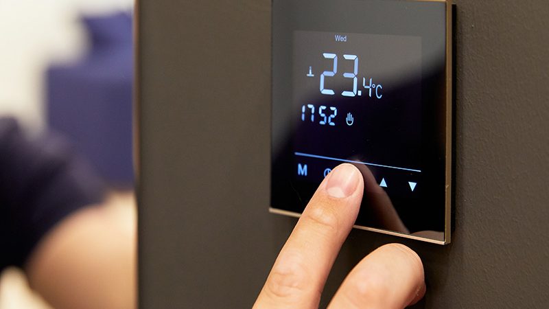 Une personne en train de modifier un thermostat de chauffage